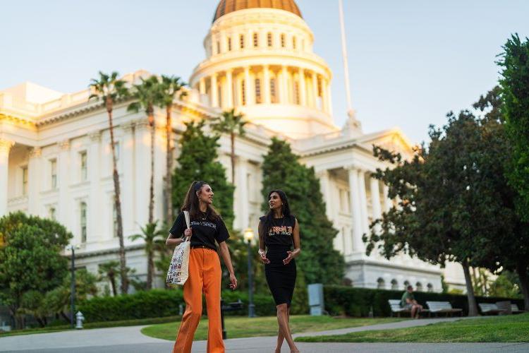 Two girls walk in front of the California State Capitol Building